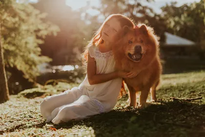 Niña abrazando a su perro en un jardín al atardecer