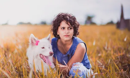 Mujer sentada en el campo junto a su perro blanco