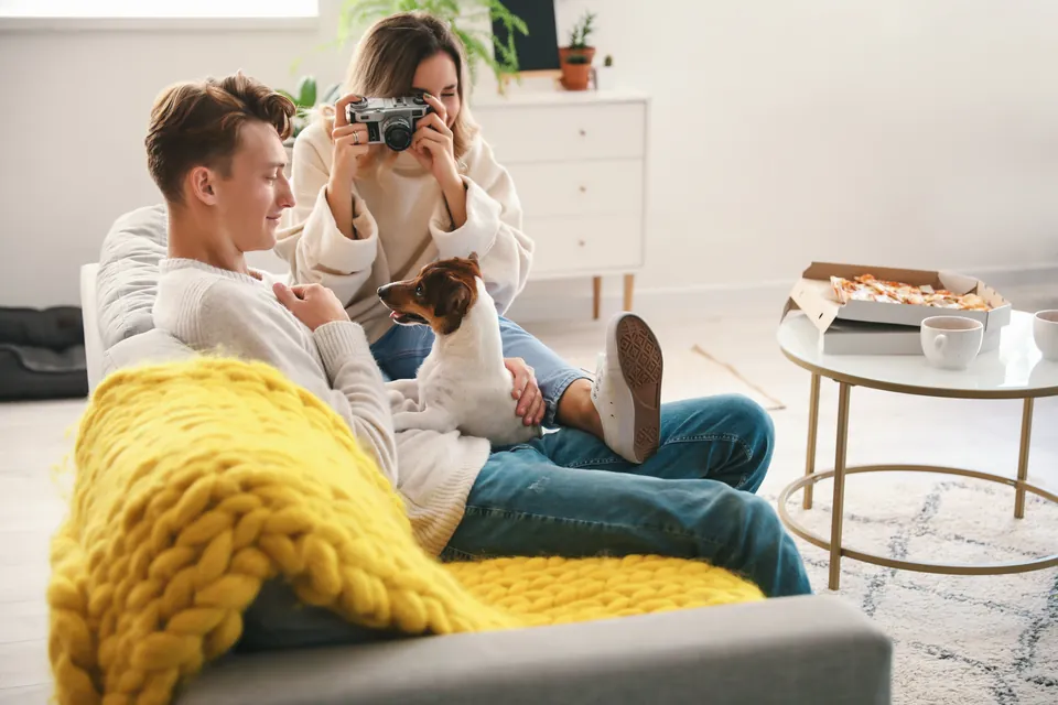 Pareja tomando fotos a su perro en la sala de su casa